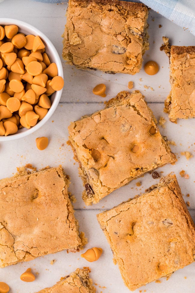 butterscotch blondies cut into squares on a counter with butterscotch chips in a bowl