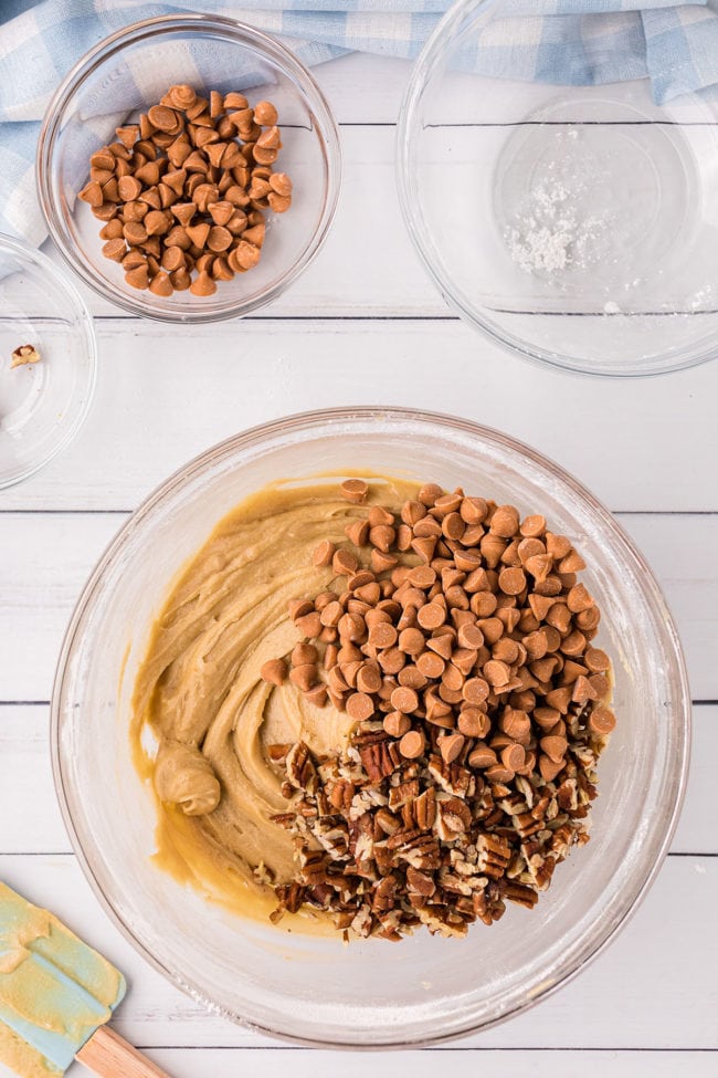 butterscotch brownie batter with butterscotch chips and peans in a glass mixing bowl