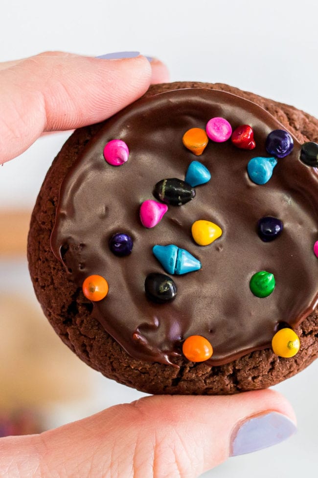 woman's hand holding a brownie cookie with rainbow chips