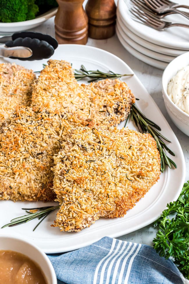 parmesan crusted baked pork chops on a platter with fresh rosemary