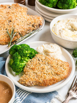 parmesan crusted baked pork chops on a plate with broccoli and mashed potatoes