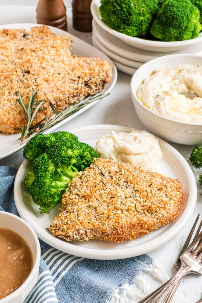 parmesan crusted baked pork chops on a plate with broccoli and mashed potatoes