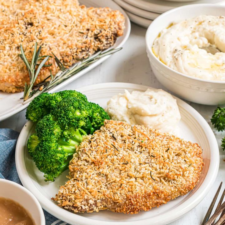 parmesan crusted baked pork chops on a plate with broccoli and mashed potatoes