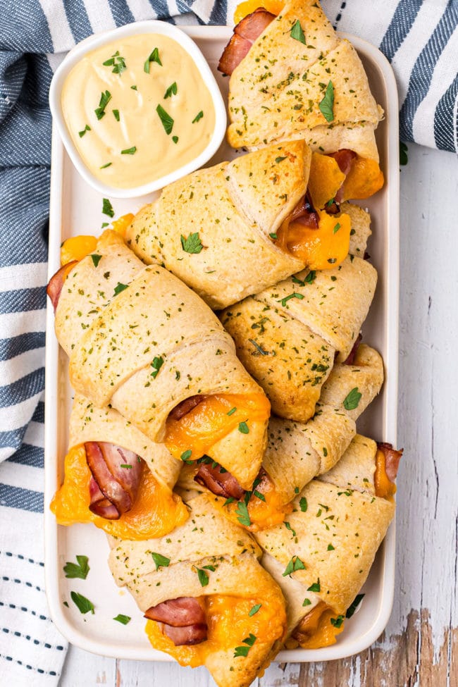Baked Ham and Cheese Crescent Roll Sandwiches on a white tray with a blue striped towel