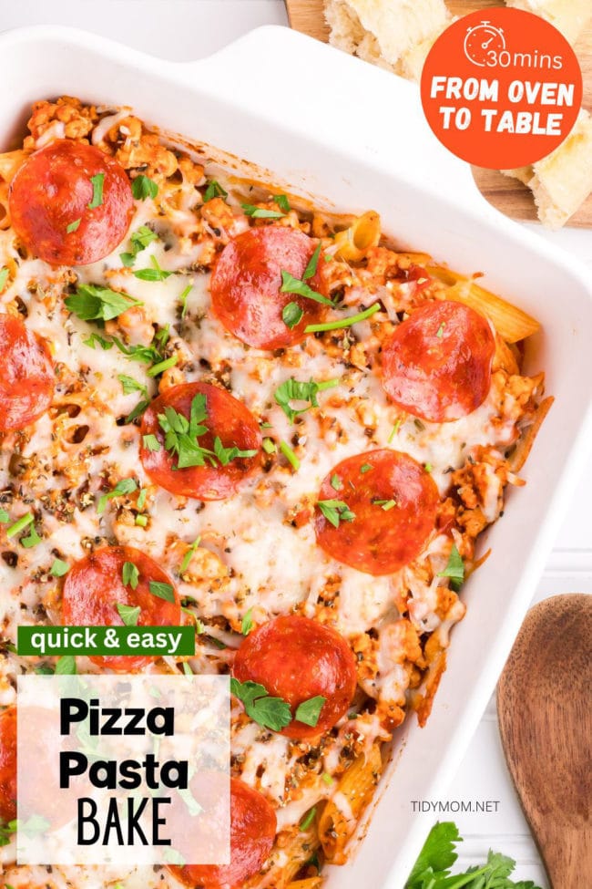 baked pizza pasta casserole with pepperoni in a white baking dish with fresh parsley garnish