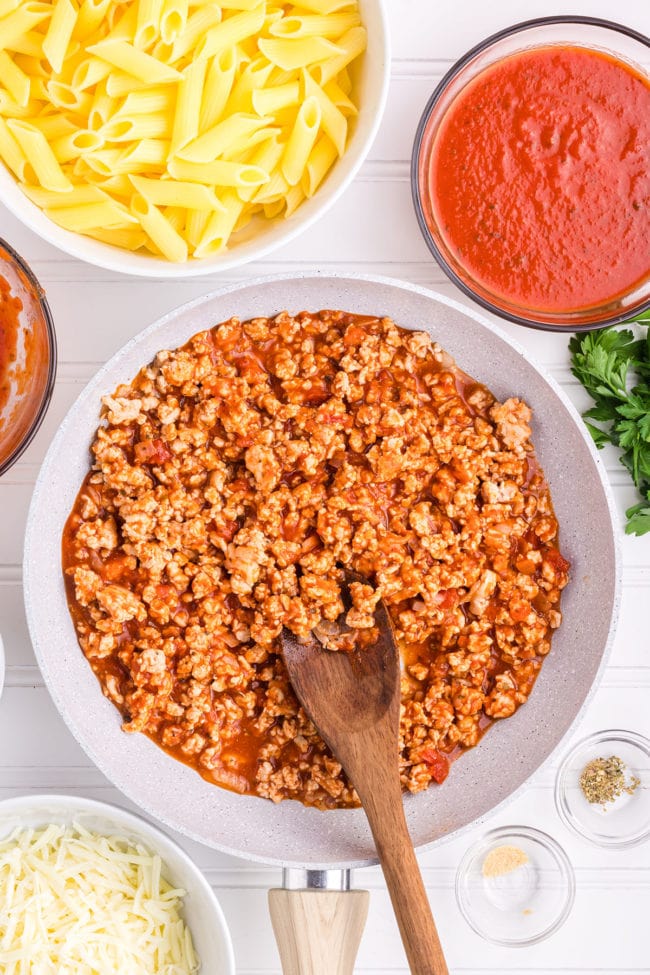 browning ground chicken with red pizza sauce in a skillet