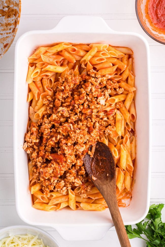 cooked pasta, ground chicken in red sauce in a baking dish