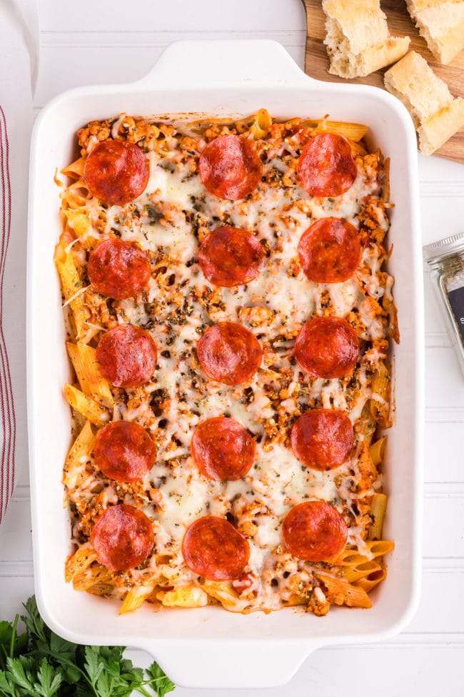 baked pizza pasta casserole with pepperoni in a white baking dish