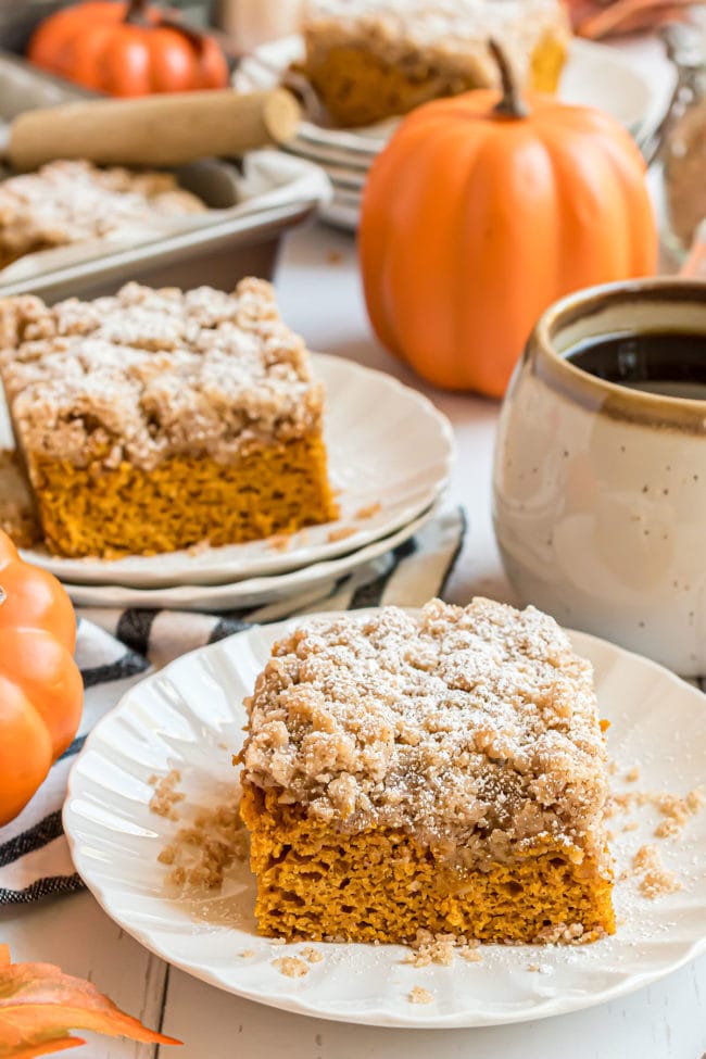 Two servings of cake with a mug of coffee and a pumpkin in the background