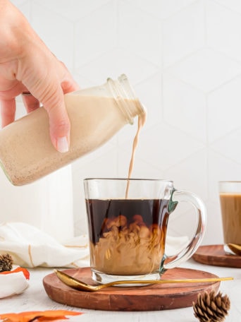 Pouring homemade Pumpkin Spice Creamer into a clear mug of coffee