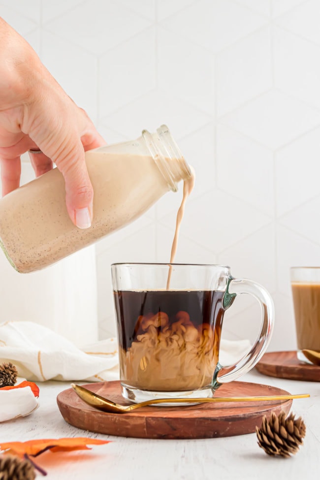 Pouring homemade Pumpkin Spice Creamer into a clear mug of coffee