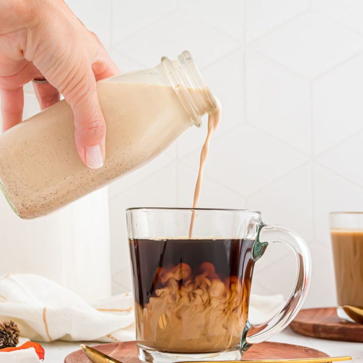 Pouring homemade Pumpkin Spice Creamer into a clear mug of coffee