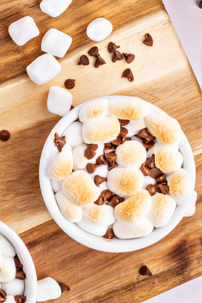 s'mores dip in a white bowl with toasted marshmallows and chocolate chips
