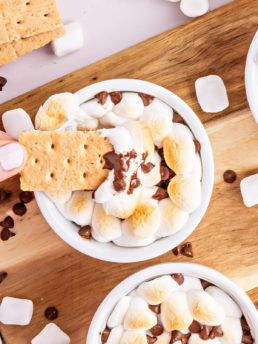 dipping a graham cracker in a warm bowl of melted chocolate and toasted marshmallows.