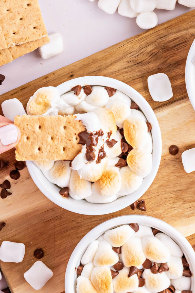 dipping a graham cracker in a warm bowl of melted chocolate and toasted marshmallows.