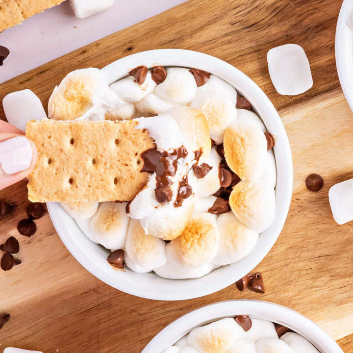 dipping a graham cracker in a warm bowl of melted chocolate and toasted marshmallows.
