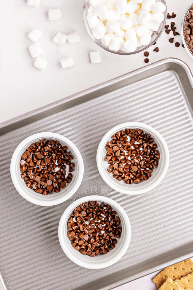 3 ramekins with chocolate chips on a baking sheet