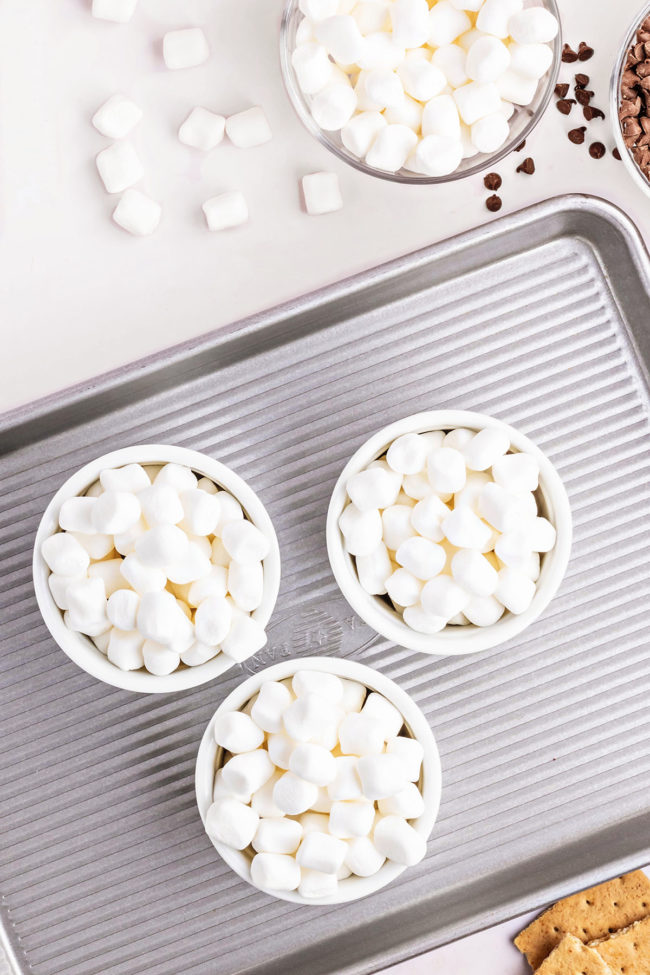 3 ramekins with mini marshmallows on a baking sheet