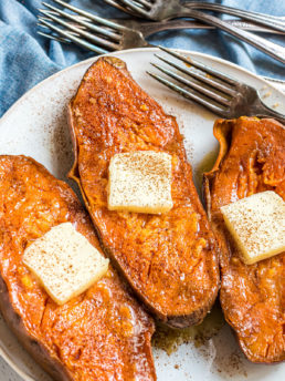 three quick baked sweet potatoes with a pat of butter and sprinkle of cinnamon
