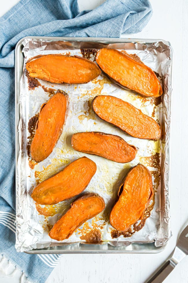 halved sweet potatoes on a baking sheet flesh side up