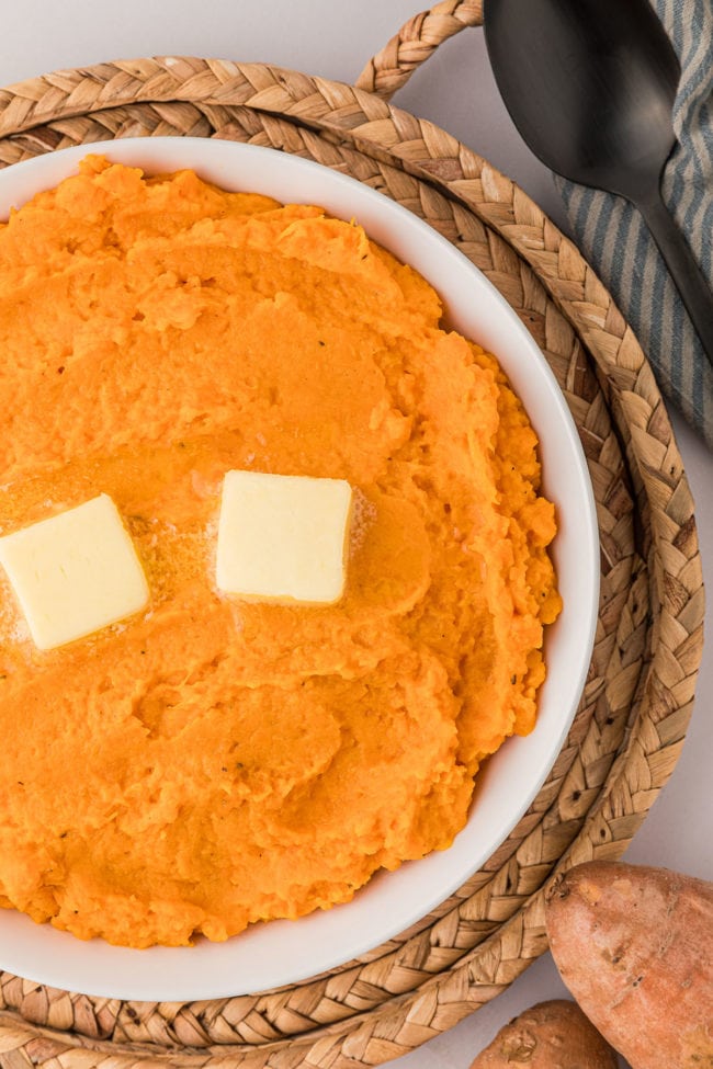 mashed sweet potatoes in a bowl with 2 pats of butter on top