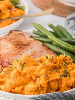 plated mashed sweet potatoes with green beans and ham