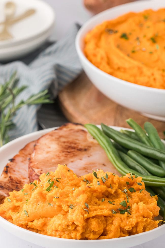 mashed sweet potatoes with green beans and ham with parsley garnish