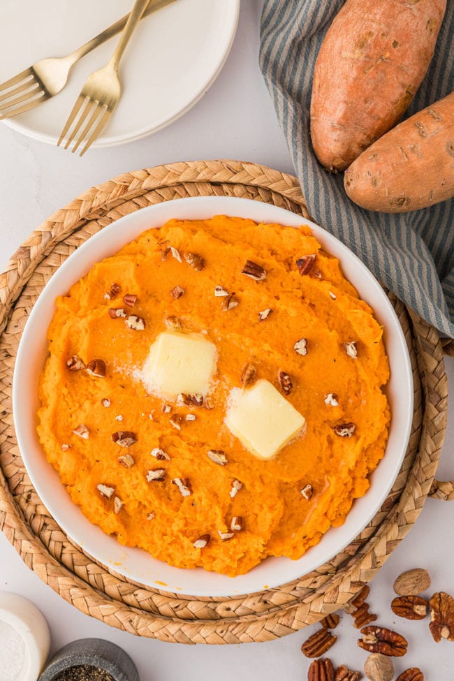 a bowl of mashed sweet potatoes topped with chopped pecans and butter