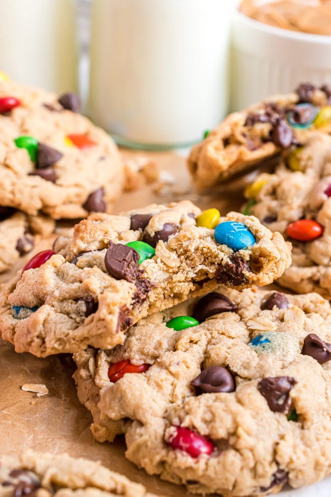 cookies on a counter with M&M's ad chocolate chips with bottle of milk in the background