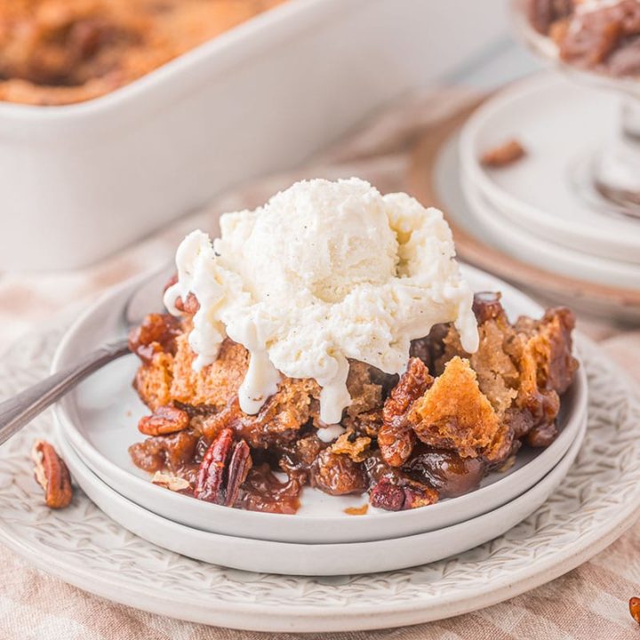 serving of pecan pie cobbler on a plate topped with vanilla ice cream