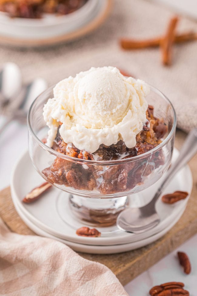serving of pecan pie cobbler in a dessert cup topped with vanilla ice cream