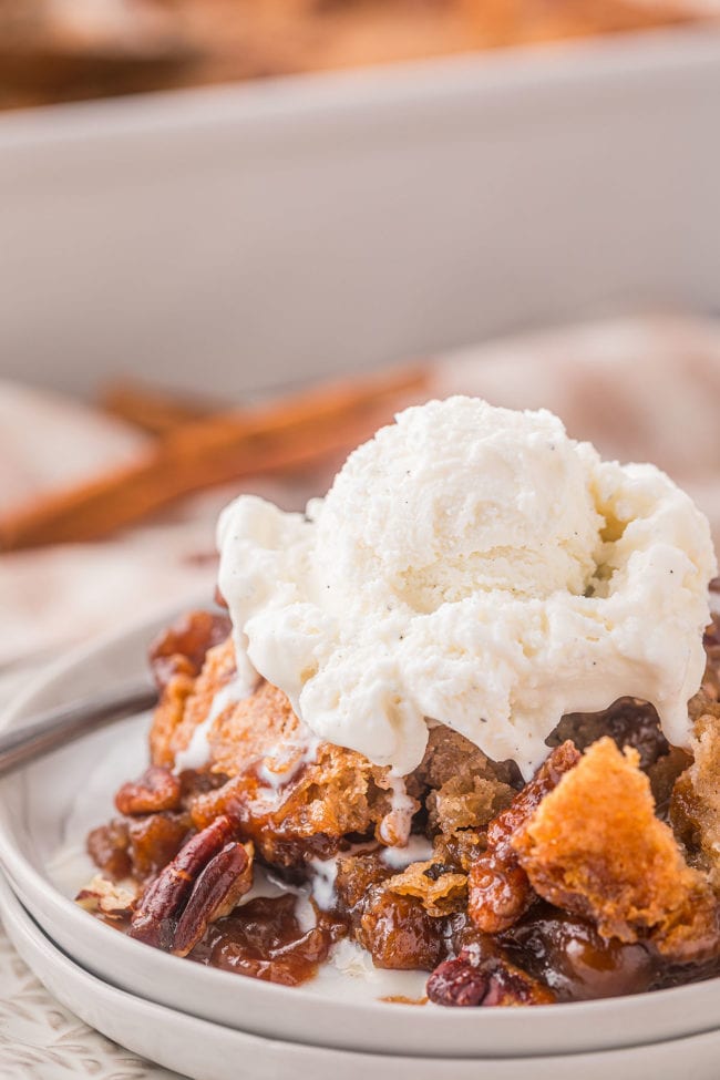serving of cobbler with pecans on a plate topped with vanilla ice cream