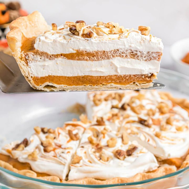 serving of layered pumpkin pie on a pie server over the pie dish.