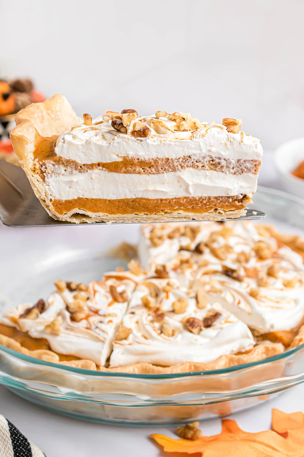 serving of layered pumpkin pie on a pie server over the pie dish.