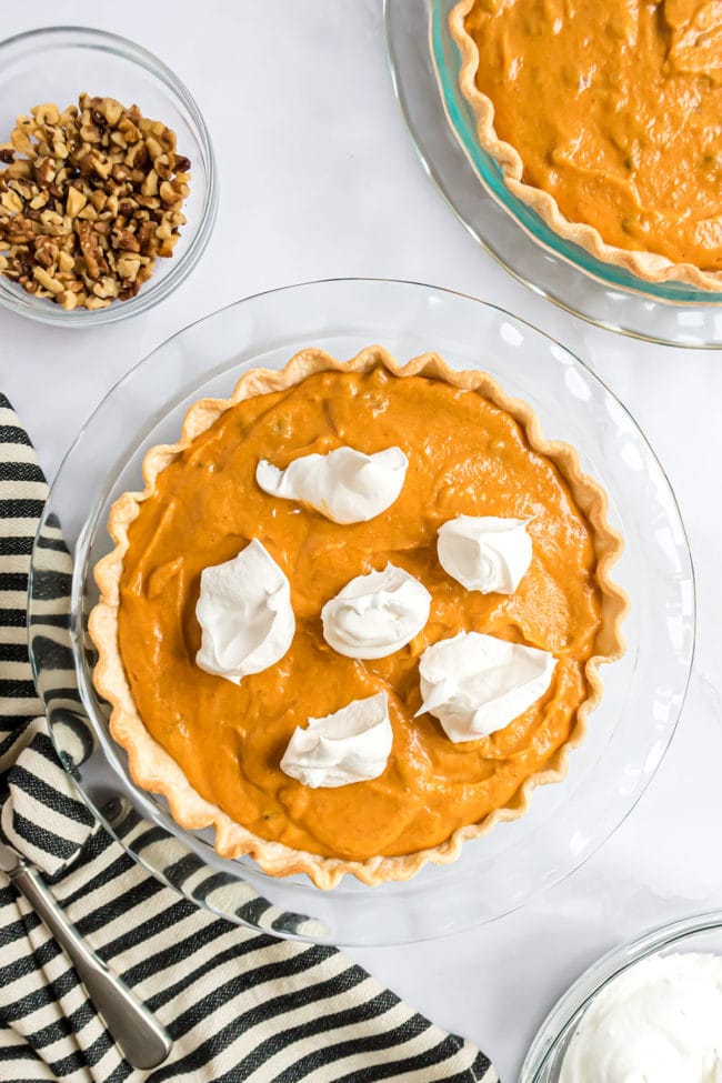 dollops of Cool Whip over pumpkin pie filling in a glass pie dish