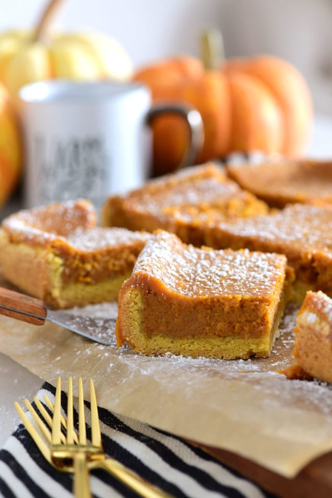 gooey butter bars on a cutting board with pumpkins and a mug in the background