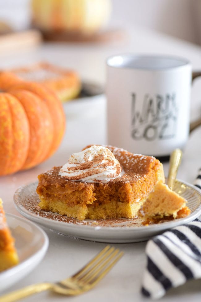 pumpkin ooey gooey cake with a mug of coffee and a pumpkin in the background