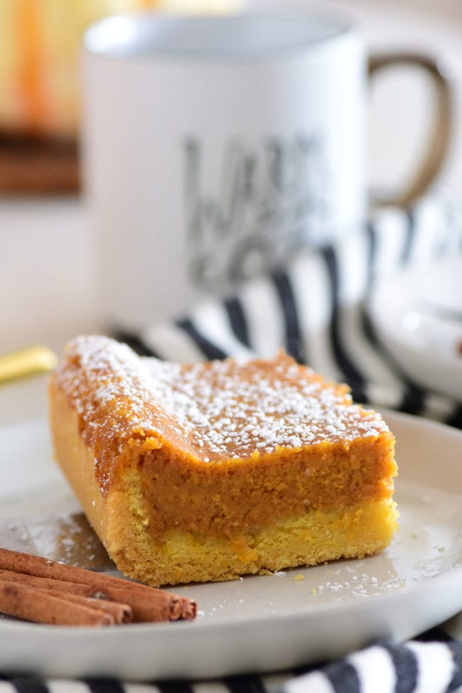 Serving of gooey pumpkin cake on a plate with a warm cup of coffee in the background