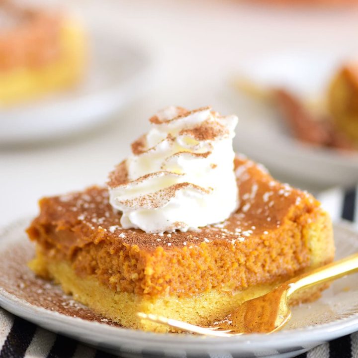 a serving of pumpkin dessert on a plate with cool whip and a gold fork