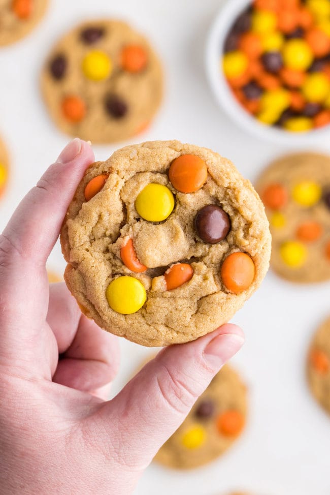 woman's hand holding a Reese's Pieces peanut butter cookie
