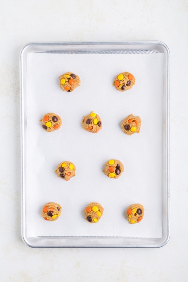 Cookie dough balls on a baking sheet with parchment paper