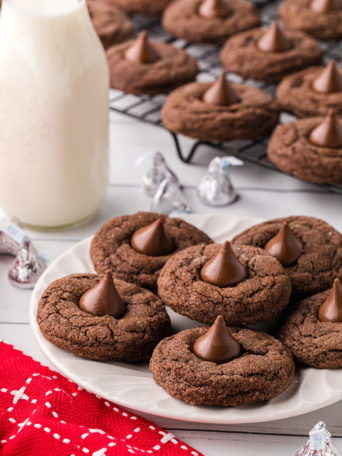 chocolate kiss cookies on a plate and cooling rack with a bottle of milk