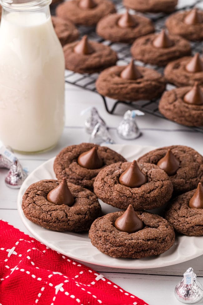 chocolate kiss cookies on a plate and cooling rack with a bottle of milk