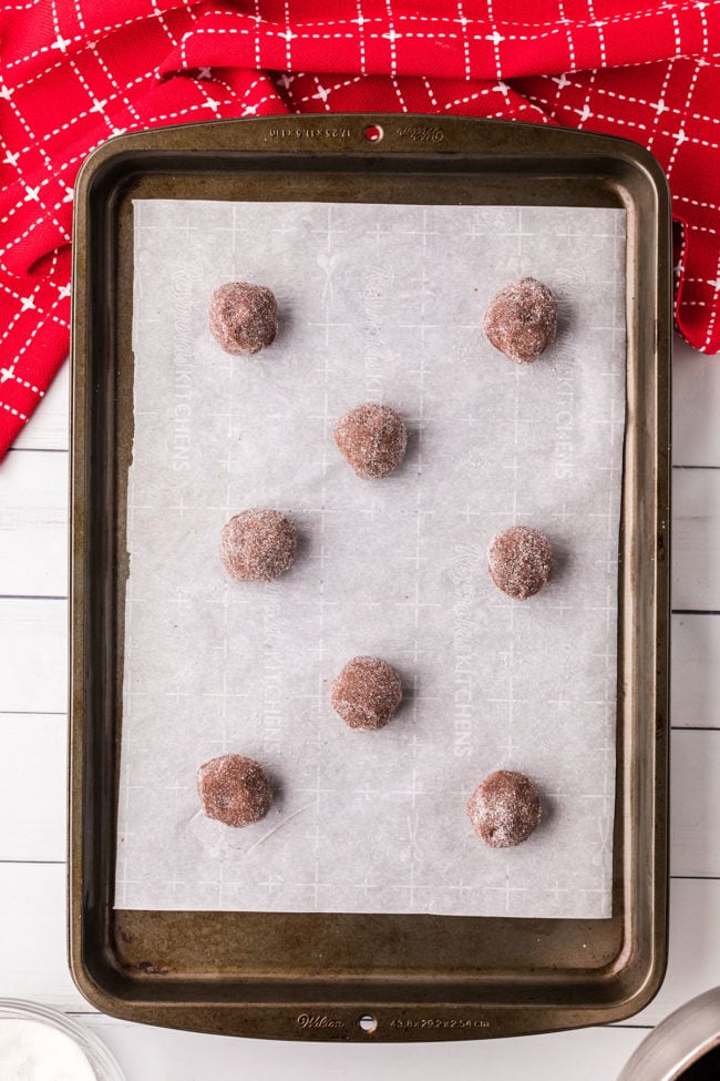 chocolate kiss cookies rolled in sugar on a sheet pan ready to bake