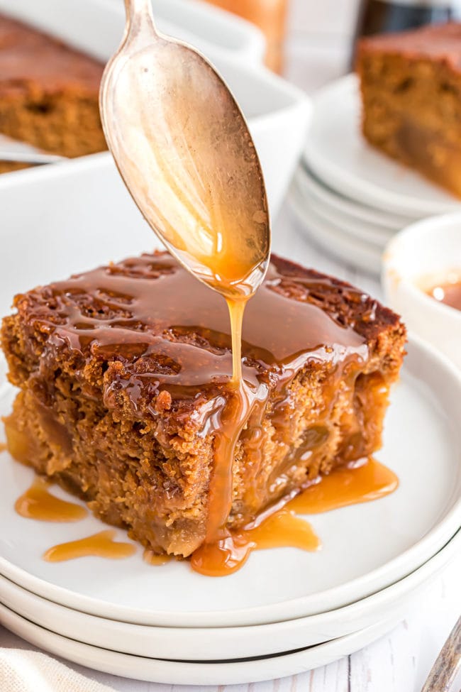 drizzling caramel syrup over a piece of apple gingerbread cake with a spoon