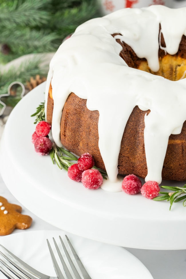 Glazed gingerbread bundt cake garnished with cranberries and fresh rosemary