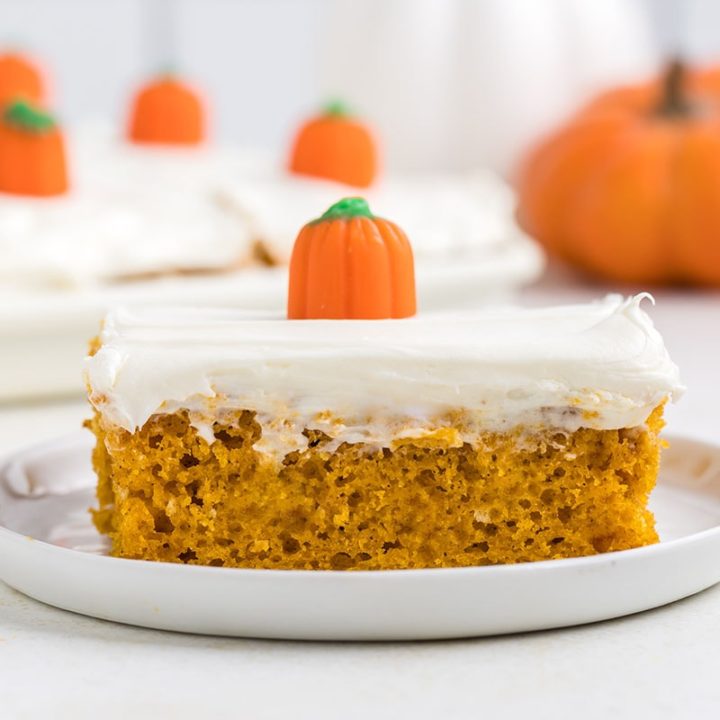 serving of fall cake with white frosting on a white plate and topped with pumpkin candy