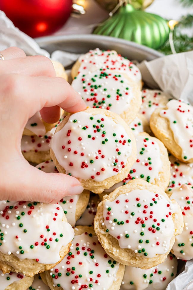 hand grabbing a ricotta cookie from a plate of cookies