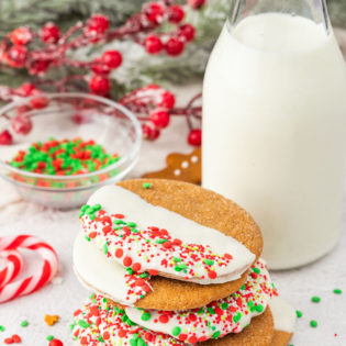 stack of chocolate dipped ginger cookies with holiday sprinkles and a bottle of milk