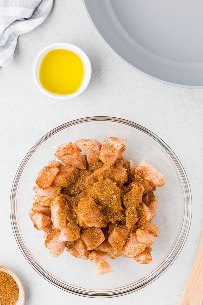 seasoned raw chicken in glass mixing bowl